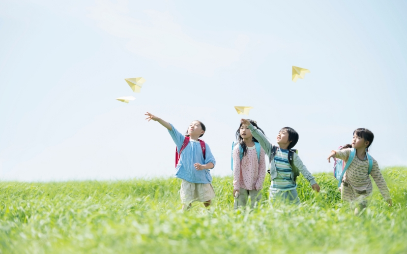 子供達が紙ヒコーキを投げている画像